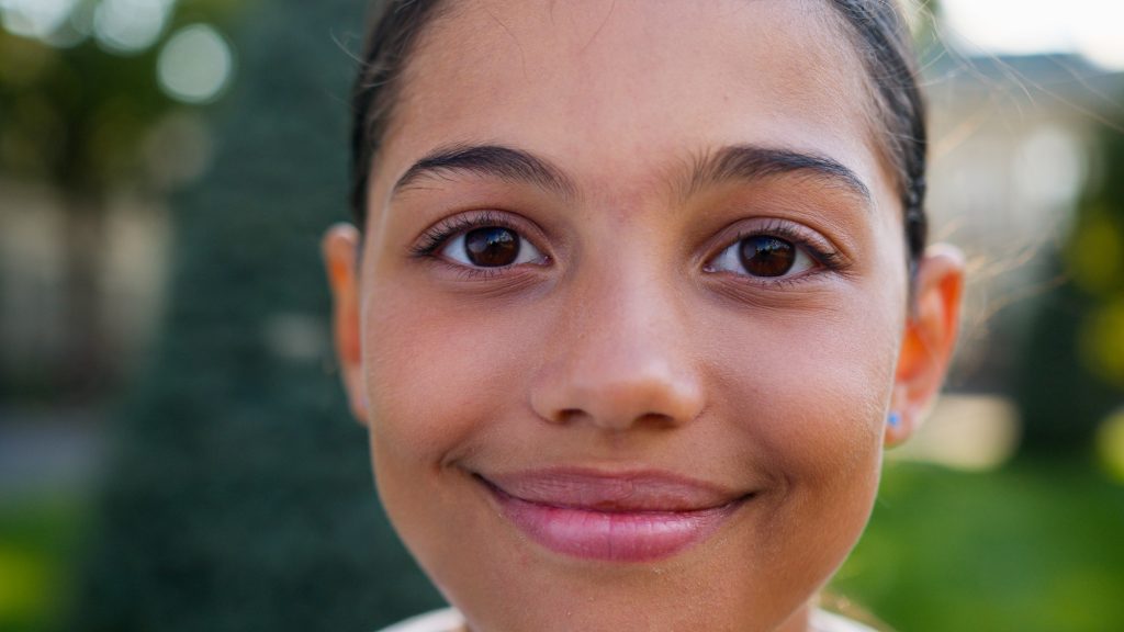 Close up girl little kid child pretty american indian latino student gen z teenager happy smiling